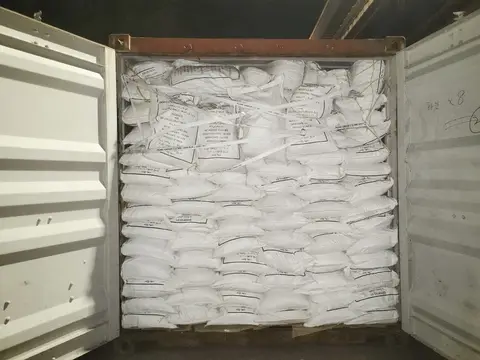 一个敞口货运集装箱,内装白色30公斤袋装货物堆至顶部,并用捆扎带固定
